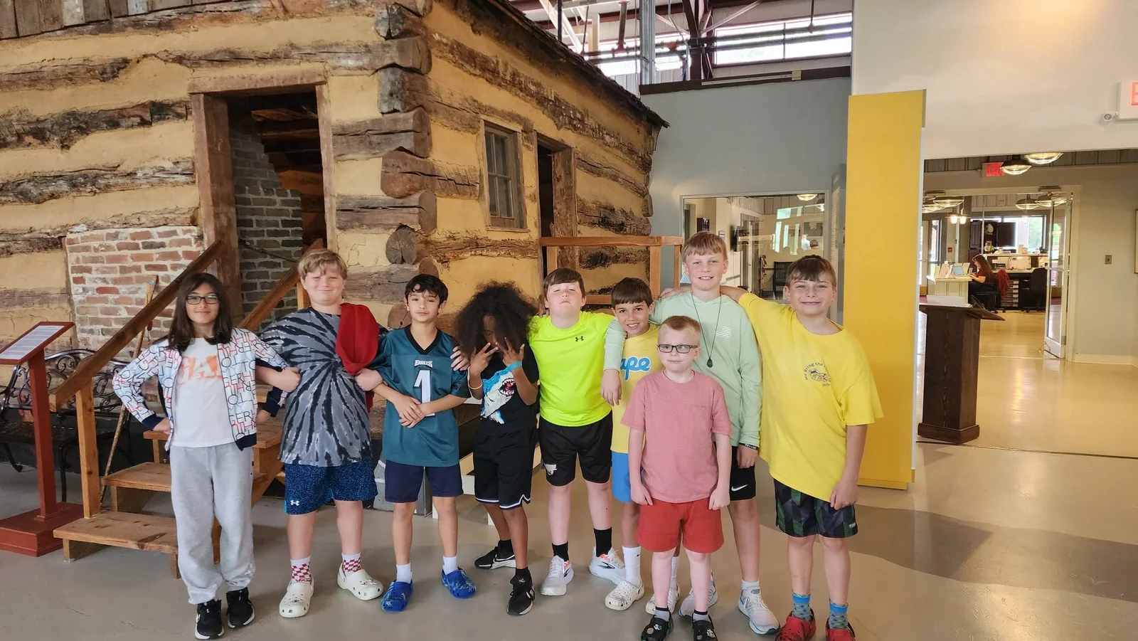 School group visiting a historic log cabin exhibit at the Delaware Agricultural Museum